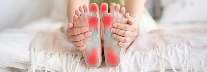 Integrated Health Care Clinic Calgary AB Foot Pain A person holding their feet. Their feet are highlighted red to indicate pain.